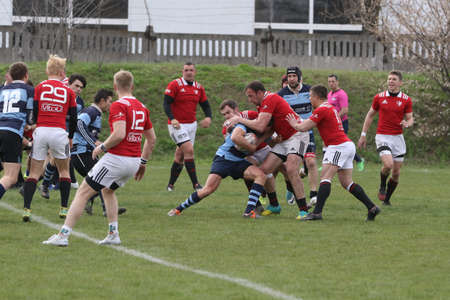 ODESSA, UKRAINE - April 17, 2021: Rugby Cup 7. Odessa Polytechnic Derby - blue, CREDO - red. Tense moment of men's rugby match. Dramatic and challenging men's rugby derby. Men fight on rugby fieldのeditorial素材