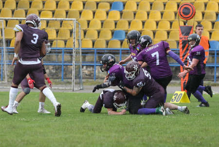 ODESSA, UKRAINE - May 30, 2021: American football on the grass. A tough duel, a battle between Odessa REINGERS and Nikolaev VIKINGS on the wet lawn of stadium. Tough American Football Athletes Battleのeditorial素材