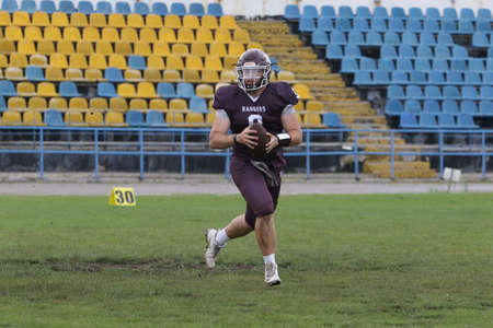 ODESSA, UKRAINE - May 30, 2021: American football on the grass. A tough duel, a battle between Odessa REINGERS and Nikolaev VIKINGS on the wet lawn of stadium. Tough American Football Athletes Battleのeditorial素材