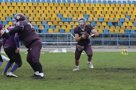 ODESSA, UKRAINE - May 30, 2021: American football on the grass. A tough duel, a battle between Odessa REINGERS and Nikolaev VIKINGS on the wet lawn of stadium. Tough American Football Athletes Battleのeditorial素材