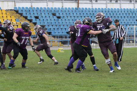 ODESSA, UKRAINE - May 30, 2021: American football on the grass. A tough duel, a battle between Odessa REINGERS and Nikolaev VIKINGS on the wet lawn of stadium. Tough American Football Athletes Battleのeditorial素材