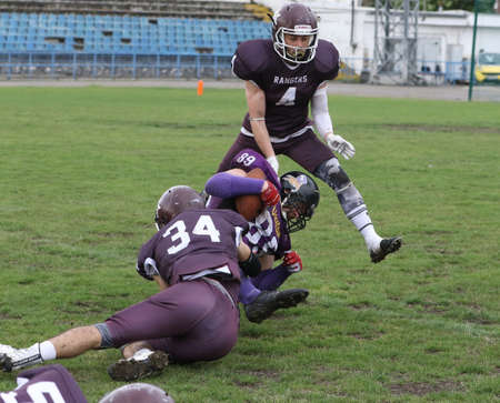 ODESSA, UKRAINE - May 30, 2021: American football on the grass. A tough duel, a battle between Odessa REINGERS and Nikolaev VIKINGS on the wet lawn of stadium. Tough American Football Athletes Battleのeditorial素材