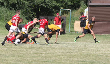 Odessa, Ukraine - June 23, 2021: Odessa National Team CREDO (red) - OLYMP-Kharkiv (yellow) in rugby 7s. Sharp aggressive fight of male rugby players for ball. Dynamic play on green grass of stadiumのeditorial素材