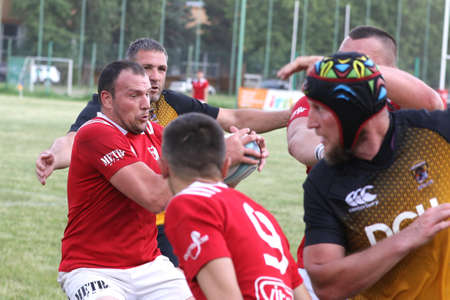 Odessa, Ukraine - June 23, 2021: Odessa National Team CREDO (red) - OLYMP-Kharkiv (yellow) in rugby 7s. Sharp aggressive fight of male rugby players for ball. Dynamic play on green grass of stadiumのeditorial素材