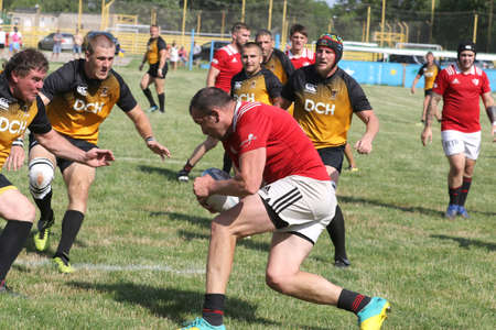 Odessa, Ukraine - June 23, 2021: Odessa National Team CREDO (red) - OLYMP-Kharkiv (yellow) in rugby 7s. Sharp aggressive fight of male rugby players for ball. Dynamic play on green grass of stadiumのeditorial素材