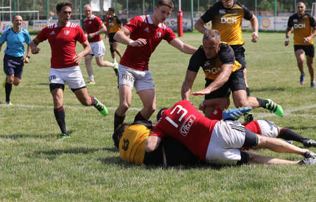 Odessa, Ukraine - June 23, 2021: Odessa National Team CREDO (red) - OLYMP-Kharkiv (yellow) in rugby 7s. Sharp aggressive fight of male rugby players for ball. Dynamic play on green grass of stadiumのeditorial素材