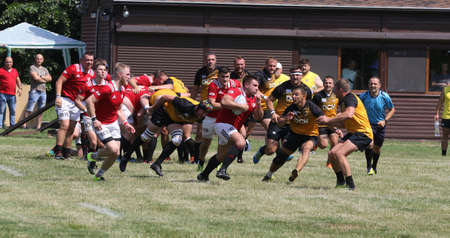 Odessa, Ukraine - June 23, 2021: Odessa National Team CREDO (red) - OLYMP-Kharkiv (yellow) in rugby 7s. Sharp aggressive fight of male rugby players for ball. Dynamic play on green grass of stadiumのeditorial素材