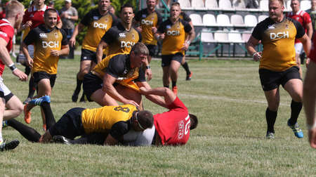 Odessa, Ukraine - June 23, 2021: Odessa National Team CREDO (red) - OLYMP-Kharkiv (yellow) in rugby 7s. Sharp aggressive fight of male rugby players for ball. Dynamic play on green grass of stadiumのeditorial素材