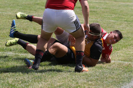Odessa, Ukraine - June 23, 2021: Odessa National Team CREDO (red) - OLYMP-Kharkiv (yellow) in rugby 7s. Sharp aggressive fight of male rugby players for ball. Dynamic play on green grass of stadiumのeditorial素材