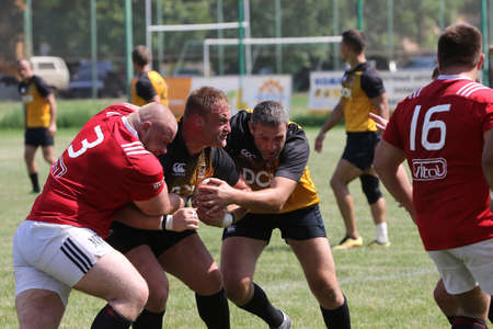 Odessa, Ukraine - June 23, 2021: Odessa National Team CREDO (red) - OLYMP-Kharkiv (yellow) in rugby 7s. Sharp aggressive fight of male rugby players for ball. Dynamic play on green grass of stadiumのeditorial素材