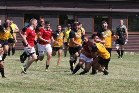Odessa, Ukraine - June 23, 2021: Odessa National Team CREDO (red) - OLYMP-Kharkiv (yellow) in rugby 7s. Sharp aggressive fight of male rugby players for ball. Dynamic play on green grass of stadiumのeditorial素材