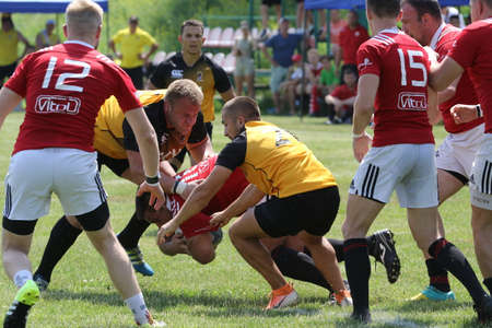 Odessa, Ukraine - June 23, 2021: Odessa National Team CREDO (red) - OLYMP-Kharkiv (yellow) in rugby 7s. Sharp aggressive fight of male rugby players for ball. Dynamic play on green grass of stadiumのeditorial素材