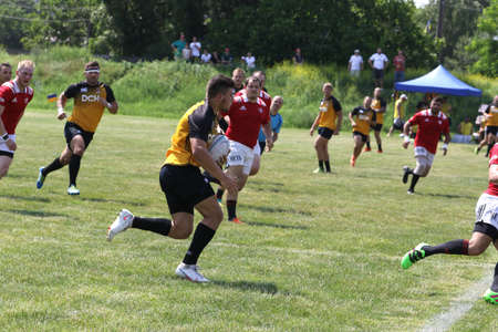 Odessa, Ukraine - June 23, 2021: Odessa National Team CREDO (red) - OLYMP-Kharkiv (yellow) in rugby 7s. Sharp aggressive fight of male rugby players for ball. Dynamic play on green grass of stadiumのeditorial素材