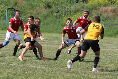 Odessa, Ukraine - June 23, 2021: Odessa National Team CREDO (red) - OLYMP-Kharkiv (yellow) in rugby 7s. Sharp aggressive fight of male rugby players for ball. Dynamic play on green grass of stadiumのeditorial素材