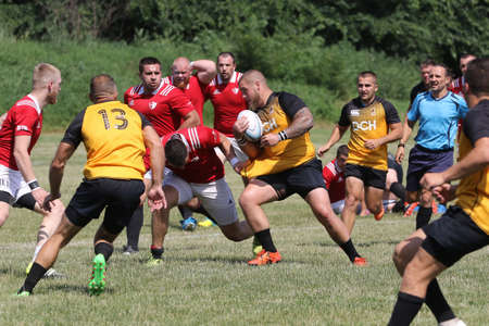 Odessa, Ukraine - June 23, 2021: Odessa National Team CREDO (red) - OLYMP-Kharkiv (yellow) in rugby 7s. Sharp aggressive fight of male rugby players for ball. Dynamic play on green grass of stadiumのeditorial素材