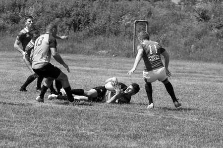 Odessa, Ukraine - June 23, 2021: Odessa National Team CREDO (red) - OLYMP-Kharkiv (yellow) in rugby 7s. Sharp aggressive fight of male rugby players for ball. Dynamic play on green grass of stadiumのeditorial素材