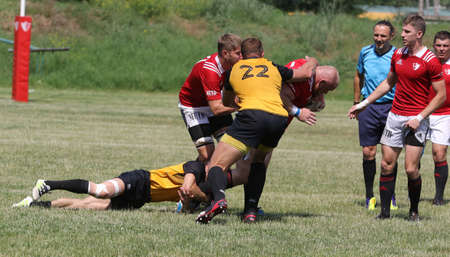 Odessa, Ukraine - June 23, 2021: Odessa National Team CREDO (red) - OLYMP-Kharkiv (yellow) in rugby 7s. Sharp aggressive fight of male rugby players for ball. Dynamic play on green grass of stadiumのeditorial素材