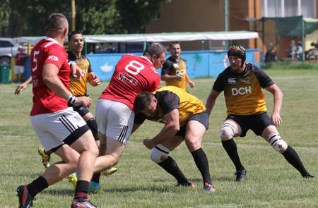 Odessa, Ukraine - June 23, 2021: Odessa National Team CREDO (red) - OLYMP-Kharkiv (yellow) in rugby 7s. Sharp aggressive fight of male rugby players for ball. Dynamic play on green grass of stadiumのeditorial素材