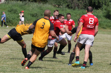 Odessa, Ukraine - June 23, 2021: Odessa National Team CREDO (red) - OLYMP-Kharkiv (yellow) in rugby 7s. Sharp aggressive fight of male rugby players for ball. Dynamic play on green grass of stadiumのeditorial素材