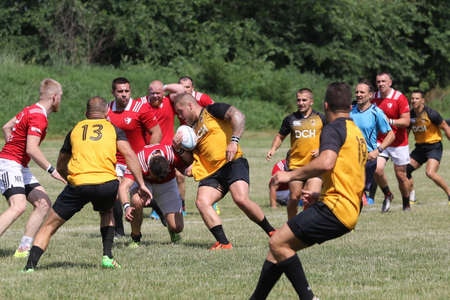 Odessa, Ukraine - June 23, 2021: Odessa National Team CREDO (red) - OLYMP-Kharkiv (yellow) in rugby 7s. Sharp aggressive fight of male rugby players for ball. Dynamic play on green grass of stadiumのeditorial素材