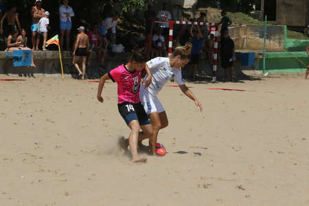 ODESSA, UKRAINE July 8, 2021: Ukrainian Beach Soccer Women's Cup. The girl's footballers are desperately playing beach soccer on sand of sea city beach on a hot sunny day. Women's soccer on sandのeditorial素材