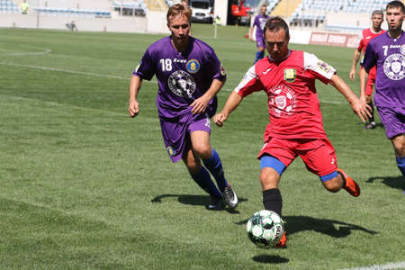 ODESSA, UKRAINE - aug 24, 2021: Football. Traditional Cup of Ukraine among ATO veterans. Veterans play football on green lawn of stadium. Game moment of football fight for cup. Vivid emotions of gameのeditorial素材