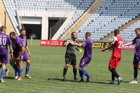ODESSA, UKRAINE - aug 24, 2021: Football. Traditional Cup of Ukraine among ATO veterans. Veterans play football on green lawn of stadium. Game moment of football fight for cup. Vivid emotions of gameのeditorial素材