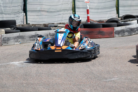 ODESSA, UKRAINE - June 18, 2022: Karting. Go Kart on track. Young positive girl racer in a helmet driving kart during car race on an auto track outdoors. extreme auto sport in sports clubのeditorial素材