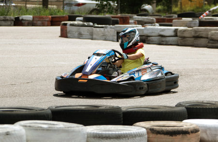 ODESSA, UKRAINE - June 18, 2022: Karting. Go Kart on track. Young positive girl racer in a helmet driving kart during car race on an auto track outdoors. extreme auto sport in sports clubのeditorial素材