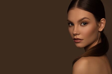 Beautiful young girl with perfect skin looks over her shoulder.の写真素材