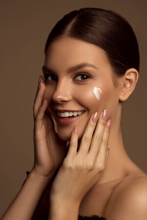 Beautiful young girl with flawless skin with cream on her face.の写真素材