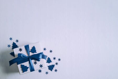Gift box or present box with blue ribbon and stars confetti on a white table top view.の写真素材