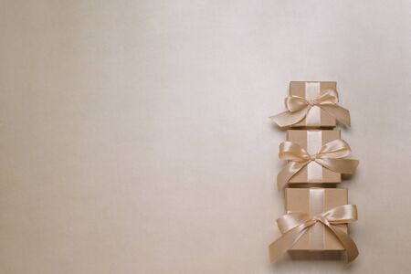 .Three gift or present boxes with a gold ribbon on a gold table top view.の写真素材