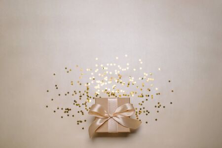 Gift or present gold box and stars confetti on gold table top view.
