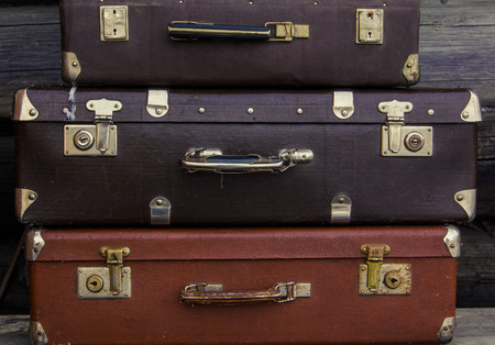 Vintage suitcases of different sizes and colors are on each other on a wooden gray backgroundの写真素材