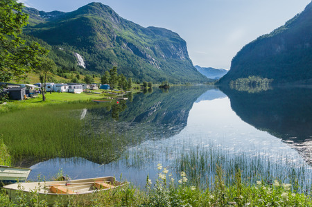Traditional norwegain campsite by the lake and mountains reflection on the waterの写真素材