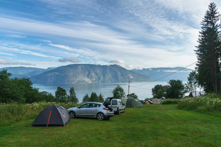 Camping area near fjord with cars and tents on grassの写真素材