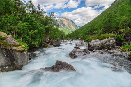 Flowing rapid mountain river in norwegian sunny valleyの写真素材