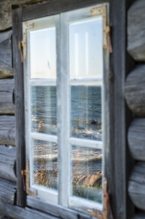 Seashore reflection in rustic cottage window of old wooden piscatorial houseの写真素材