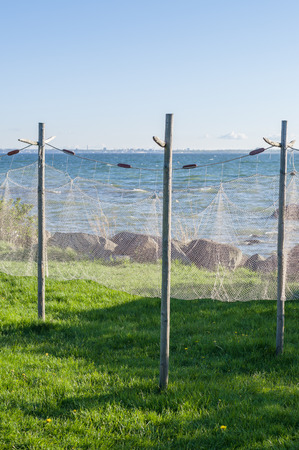 Old style fishing net hanging to dry near seashoreの写真素材