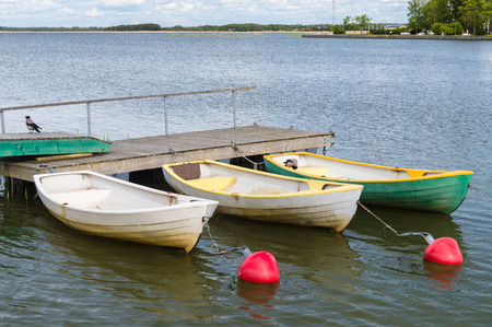 Three rowboats at wooden dock with buoy waiting for customersの写真素材