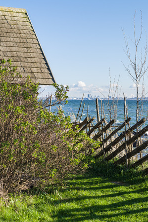 Rustic house and hedge on seashore and city on backgroundの写真素材