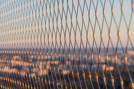 Metal mesh wire fence closeup on sunset lightの写真素材