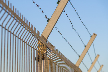 Security post with barbed wire fence closeupの写真素材