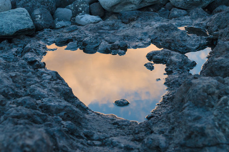 Sunset reflection in small puddle on volcanic groundの写真素材
