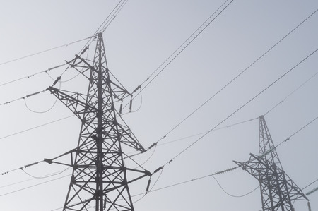 Electric high voltage power towers at morning mistの写真素材