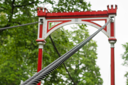 Retro style bridge in the rain, selective focus on steel ropes bundle
