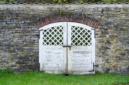 White weathered wooden gate in old limestone wallの写真素材