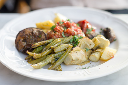 Vegetable plate of marinated green beans and bell peppers, fried artichokes and potatoes, grilled eggplant, oven-baked champignons and tomato, shallow depth of fieldの写真素材