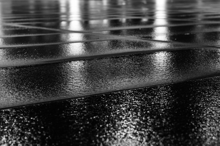Night light reflection on wet paving slab after rain. Black and white image with selective focusの写真素材